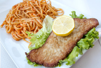 close-up of plate of pasta and pork with lettuce