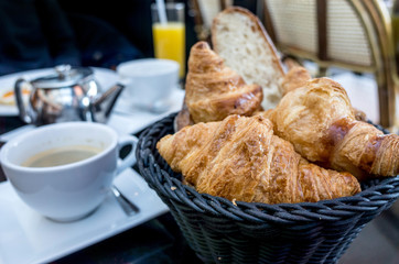 Breakfast with coffee and croissants in a basket on table