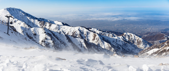 Mountains under the snow in winter. Panorama of snow mountain range landscape with blue sky.