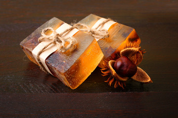 Colorful natural herbal soap related thread lying on a wooden table with a chestnut