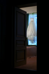 Fototapeta na wymiar Beautiful wedding dress hanging in the doorway