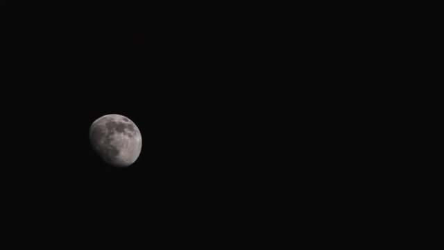 A waxing gibbous moon hangs still in a black sky