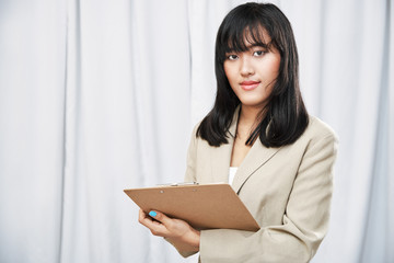 close up of businesswoman wearing beige suit standing and taking note on folder
