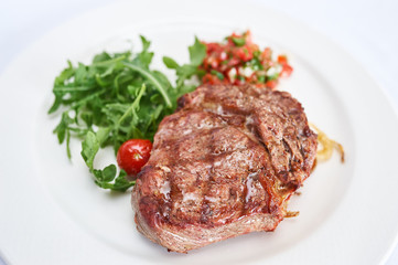 Sirloin steak with tomato tartare on white plate studio shot