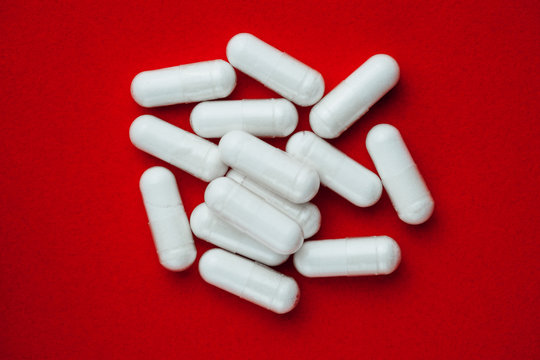 white capsules pills on red background