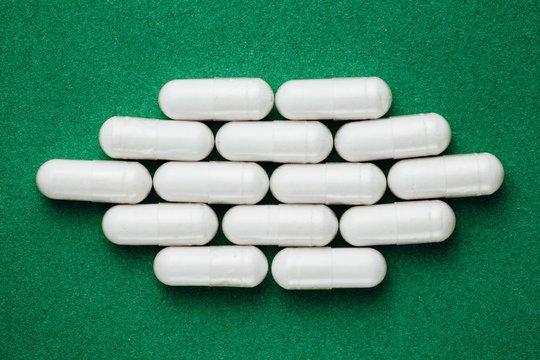 white capsules pills on green background