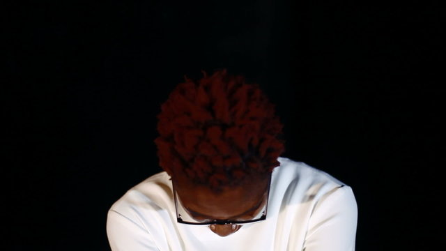 Аn insane black man in his forties wearing a straitjacket sitting in a dark of an asylum