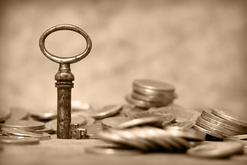 Old key and coins in sepia tone