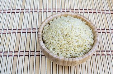 Cooked quinoa in bamboo bowl on bamboo platemat