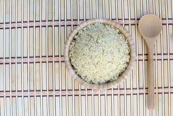 Cooked quinoa in bamboo bowl and spoon on bamboo platemat