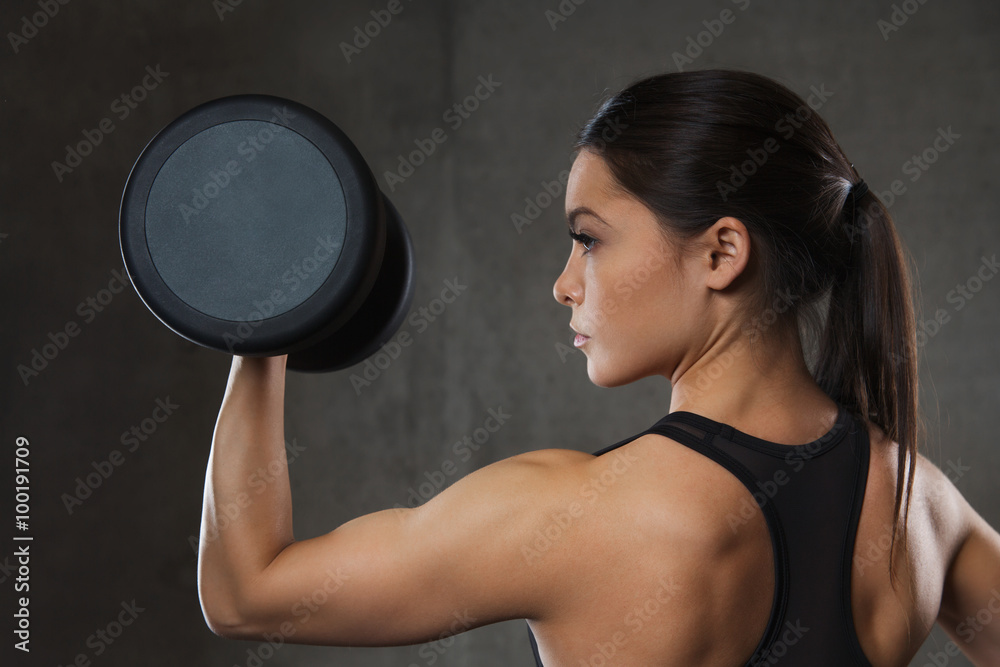 Canvas Prints young woman flexing muscles with dumbbells in gym