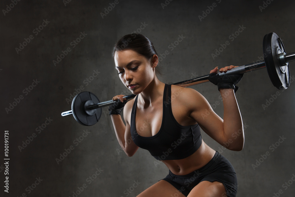 Canvas Prints young woman flexing muscles with barbell in gym