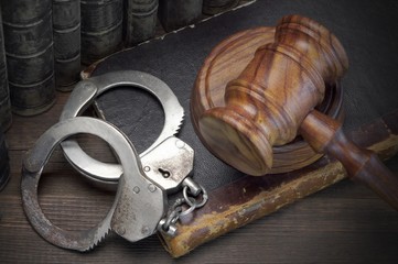 Handcuffs, Judge Gavel And Old Law Books On Wooden Table