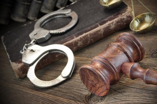 Handcuffs, Judge Gavel And Old Law Books On Wooden Table