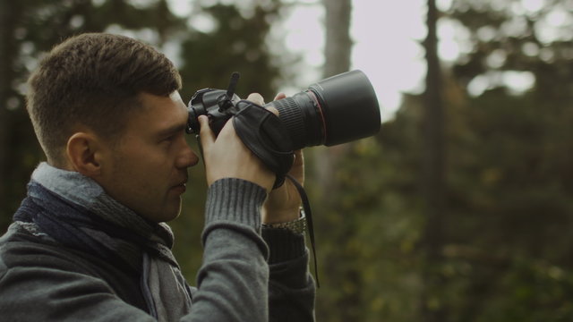 Male photographer is taking photographs in a forest at autumn time. Shot on RED Cinema Camera.