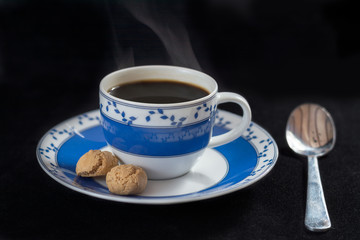 blue-white porcelain cup of hot coffee, espresso with two Italian amaretti cookies
