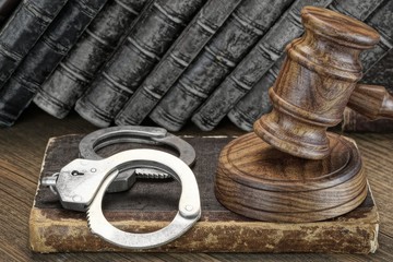 Handcuffs, Judge Gavel And Old Law Books On Wooden Table