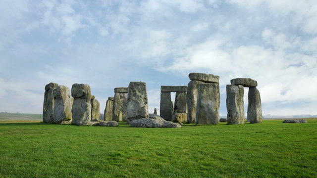 Wide time-lapse of Stonehenge with white clouds.