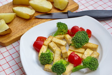 pieces of roasted tofu served with fresh vegetable and potatoes
