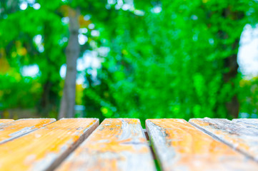 Fototapeta premium Yellow wooden planks with blurred green foliage