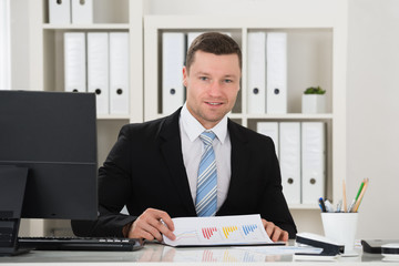 Naklejka premium Happy businessman Analyzing Financial Charts