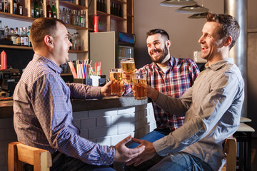 Happy friends drinking beer at counter in pub