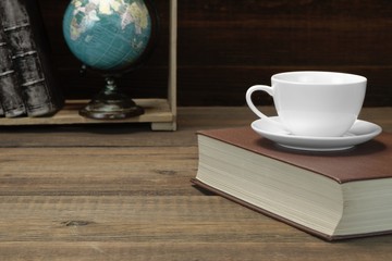 Empty Tea Cup On The Red Old Book And Bookshelf