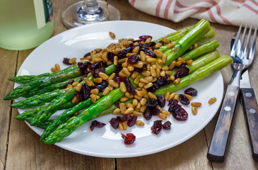Freshly cooked asparagus appetizer with pine nuts and cranberries