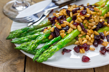 Freshly cooked asparagus appetizer with pine nuts and cranberries