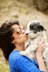 smiling young woman hugging with her small white poodle dog outdoor