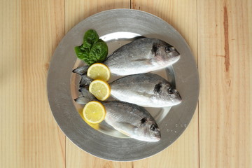 raw fish silver tray on wooden background pine
