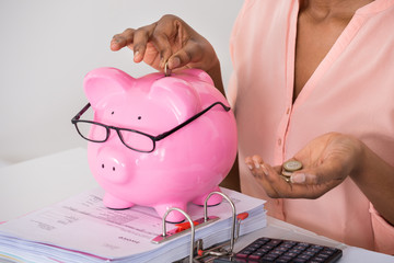 Woman Inserting Coin In Piggybank