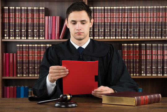 Judge Reading Legal Document At Desk