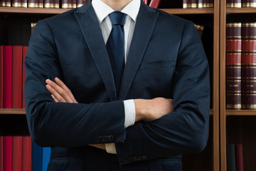 Midsection Of Lawyer Standing Against Bookshelf