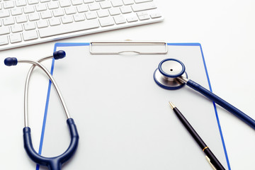 Medical stethoscope on clipboard with paper and keyboard