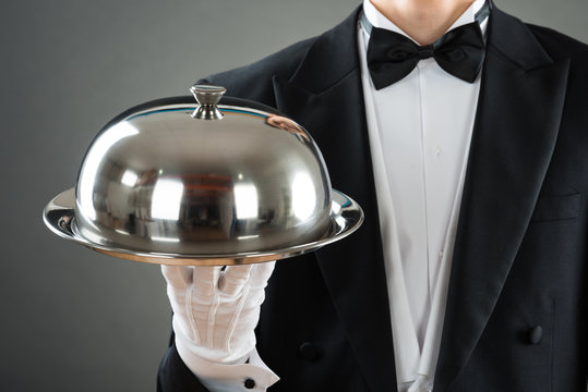 Midsection Of Waiter Holding Tray With Cloche