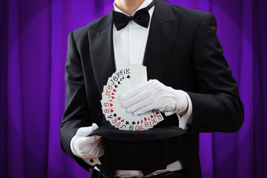 Magician Putting Playing Cards In Hat
