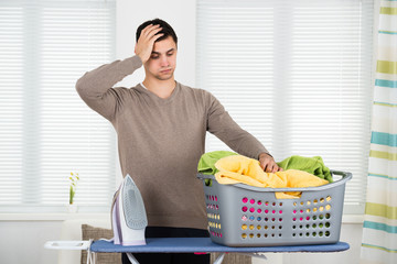 Tired Man Looking At Laundry Basket