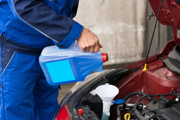 Serviceman Pouring Windshield Washer Fluid Into Car