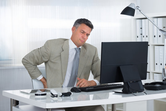 Mature Businessman Suffering From Back Pain At Desk