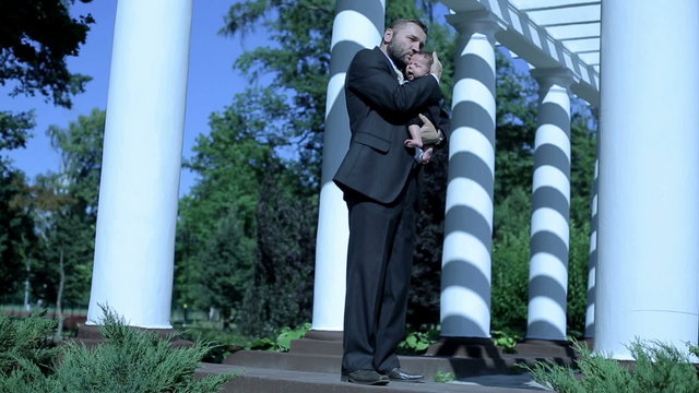 Businessman stands , hugs and kiss his child 
