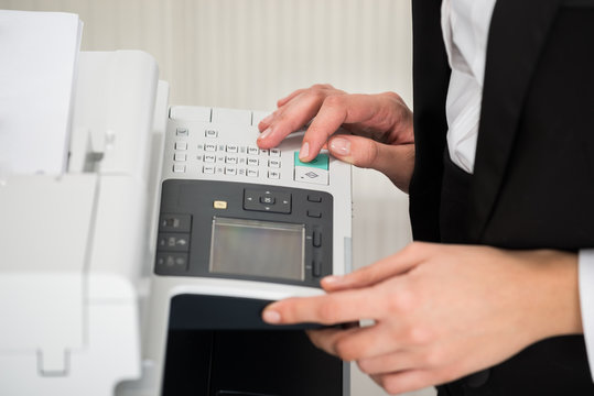 Businesswoman Operating Printer In Office