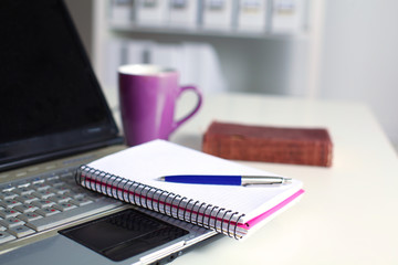 Office table with blank notepad and laptop 