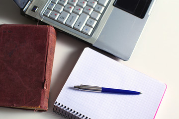 Office table with blank notepad and laptop 