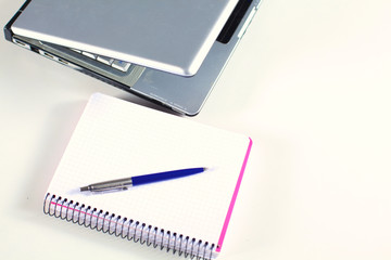 Office table with blank notepad and laptop 