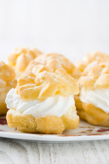 Fresh profiteroles with cream and chocolate on plate
