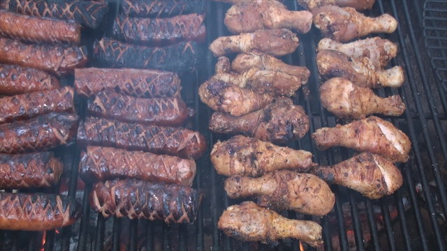 Scorching polish sausages and chicken drumsticks on the fire pit's grill