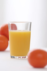 close-up on a full of vitamins glass of orange juice with oranges in the background