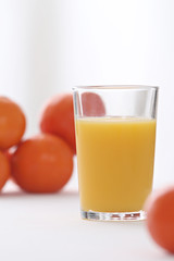 close-up on a full of vitamins glass of orange juice with oranges in the background
