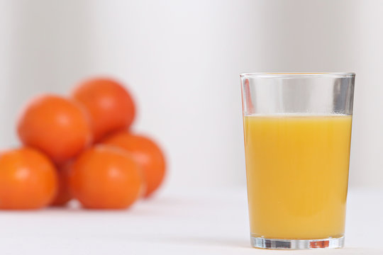 close-up on a full of vitamins glass of orange juice with oranges in the background